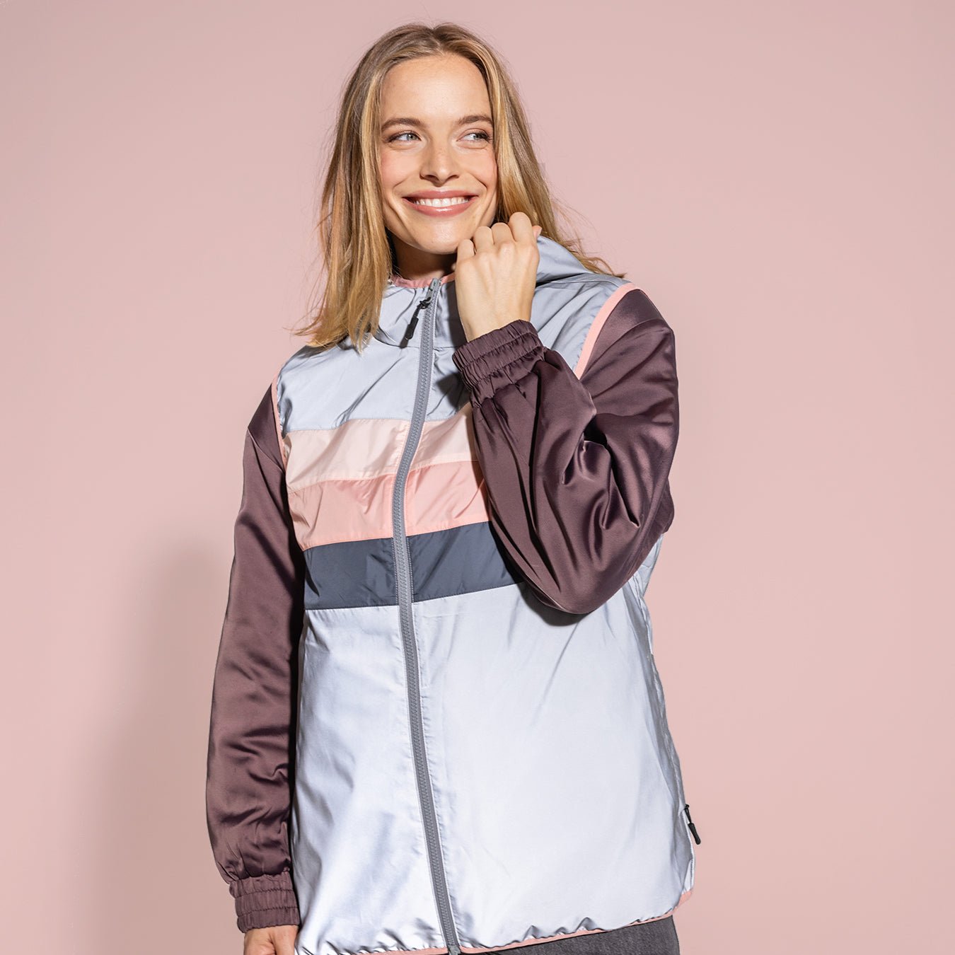 Ela Mo™ Fahrradweste. Eine Frau mit heller Fahrradweste vor rosa Hintergrund.