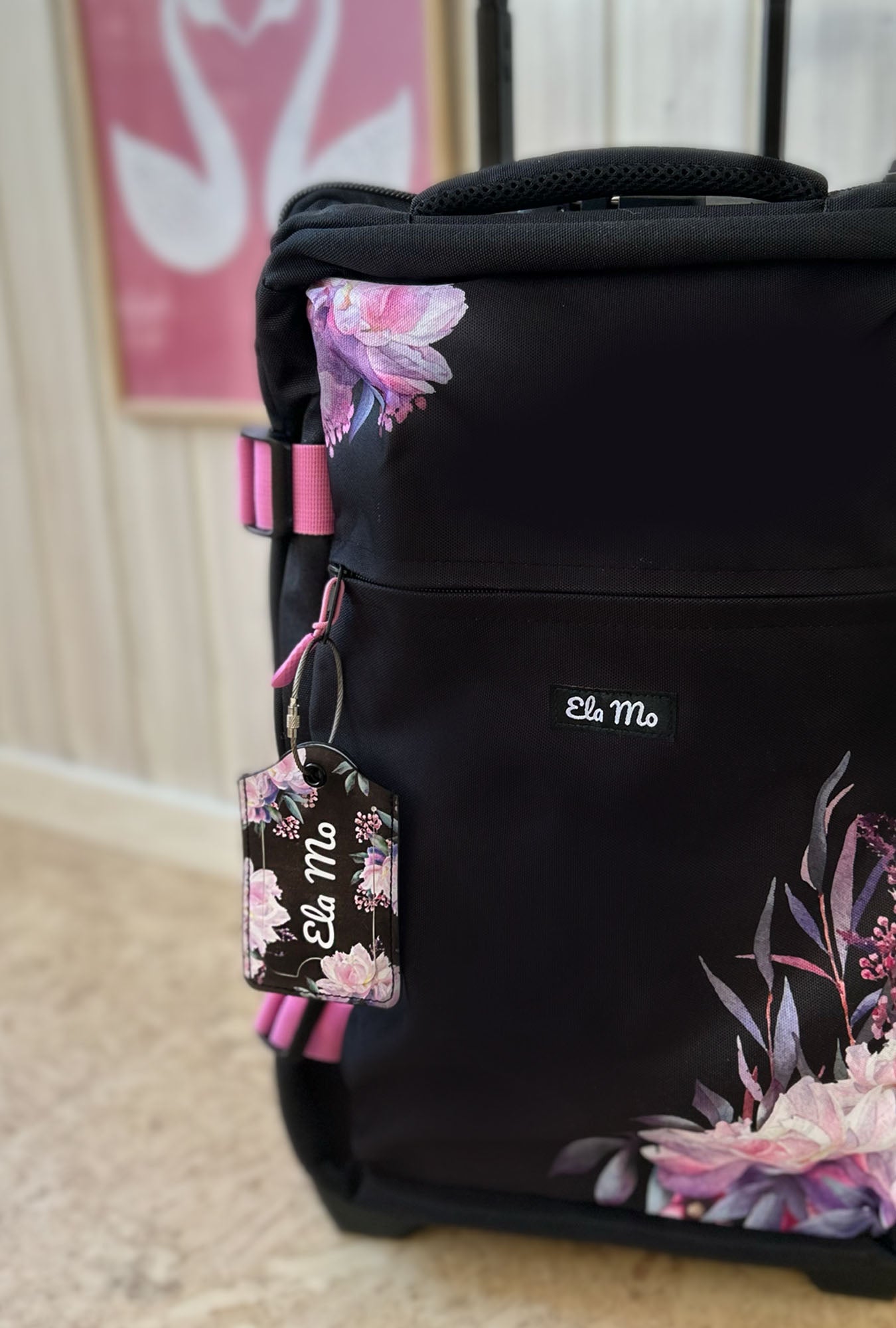 Ela Mo™ Gepäckanhänger | Beauty in Darkness. Ein geblümter Anhänger an einem geblümten schwarzen Rollkoffer.