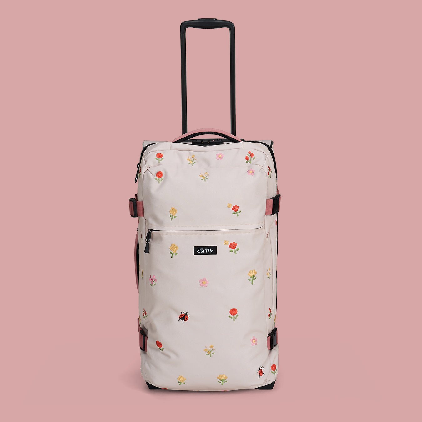 Ela Mo™ Reisetasche mit Rollen 78 Liter | Embroidery Edition Losy. Helle geblümte Tasche mit Tragegriff auf rosa Hintergrund.