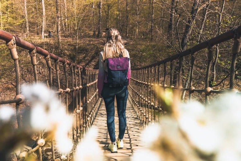 Ela Mo™ Daypack Rucksack | Berry. Eine Frau mit dem Rucksack auf dem Rücken im Freien – alltäglicher Lifestyle.