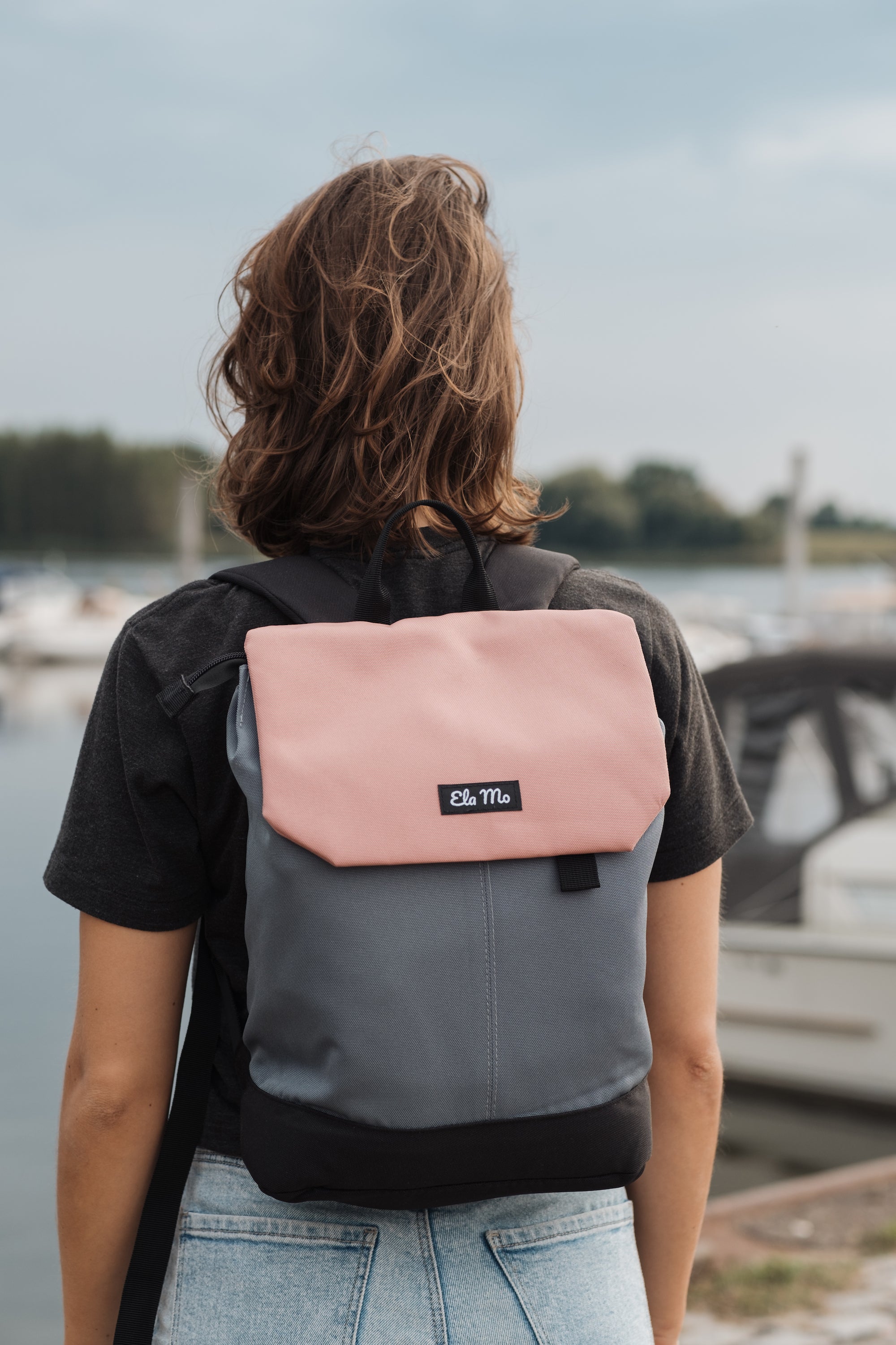 Ela Mo™ Daypack Rucksack | Salmon. Eine Frau mit dem Rucksack auf dem Rücken im Freien.