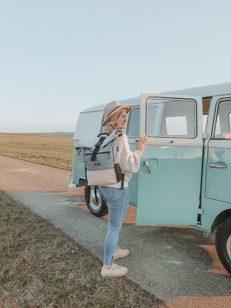 Rose On Rocks Ela Mo™ Rolltop Rucksack | Rose On Rocks. Eine Frau mit dem Rucksack auf dem Rücken – alltäglicher Lifestyle.